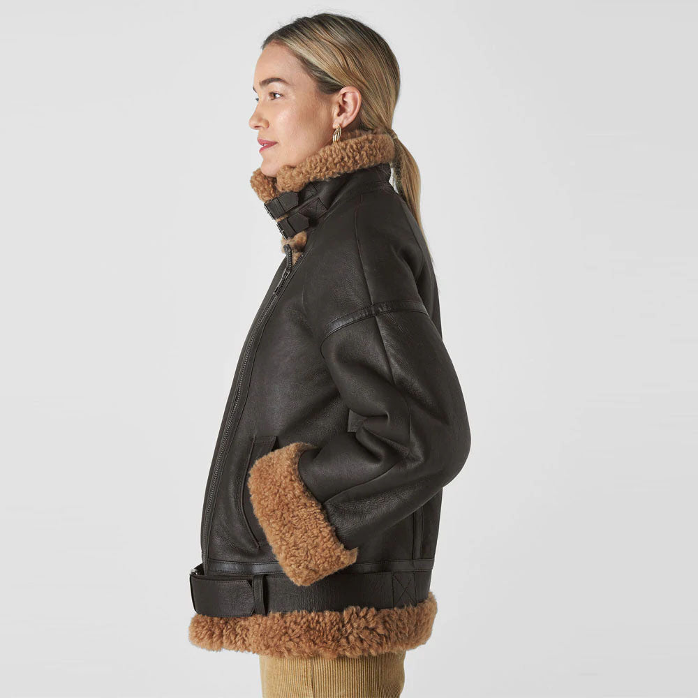 A brown shearling leather biker jacket with a standing collar, belt detailing, and fur lining at the cuffs and waist.