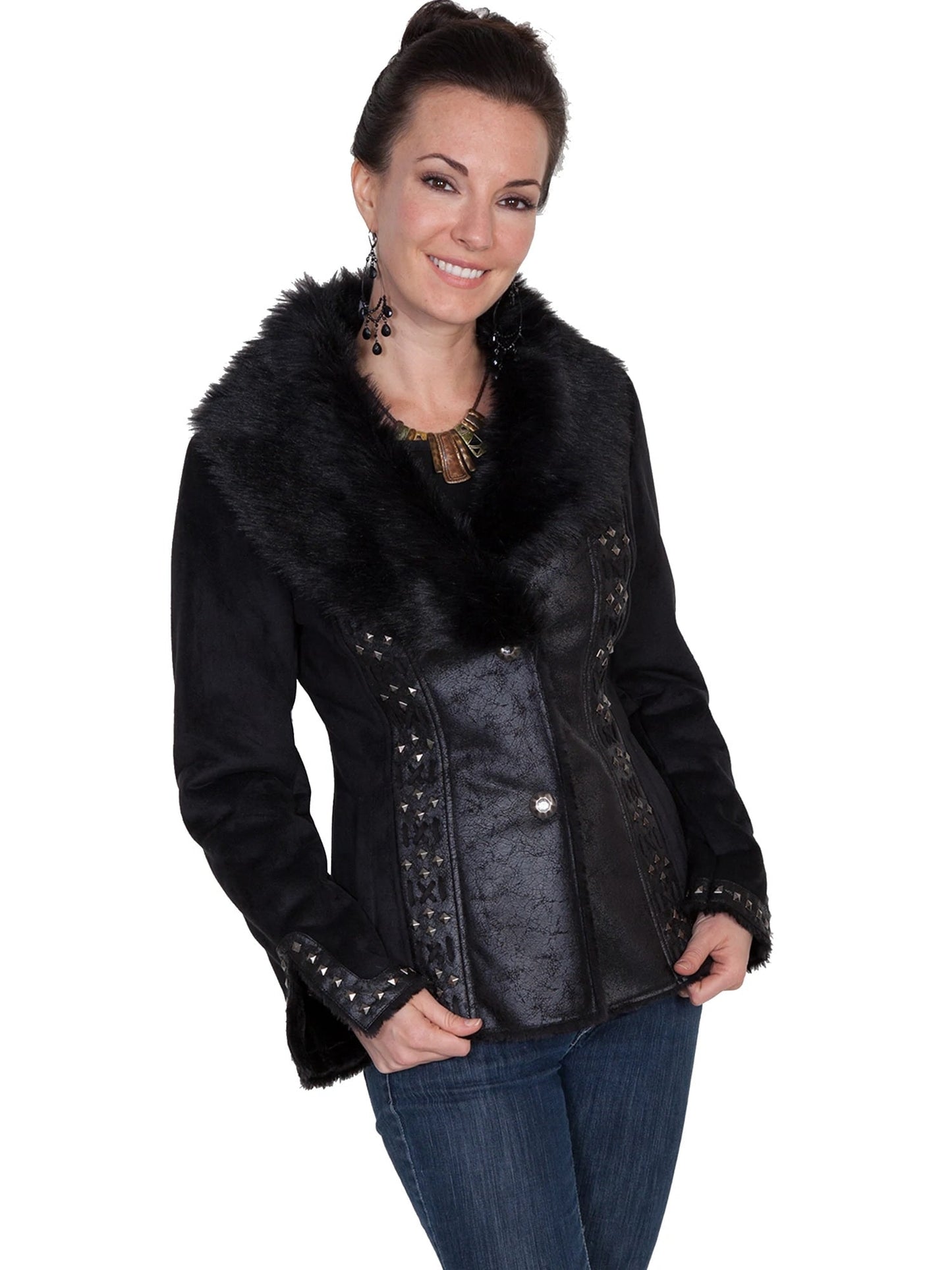 A woman smiling, wearing a black faux fur lined leather jacket with metallic buttons and stud embellishments, paired with blue jeans.